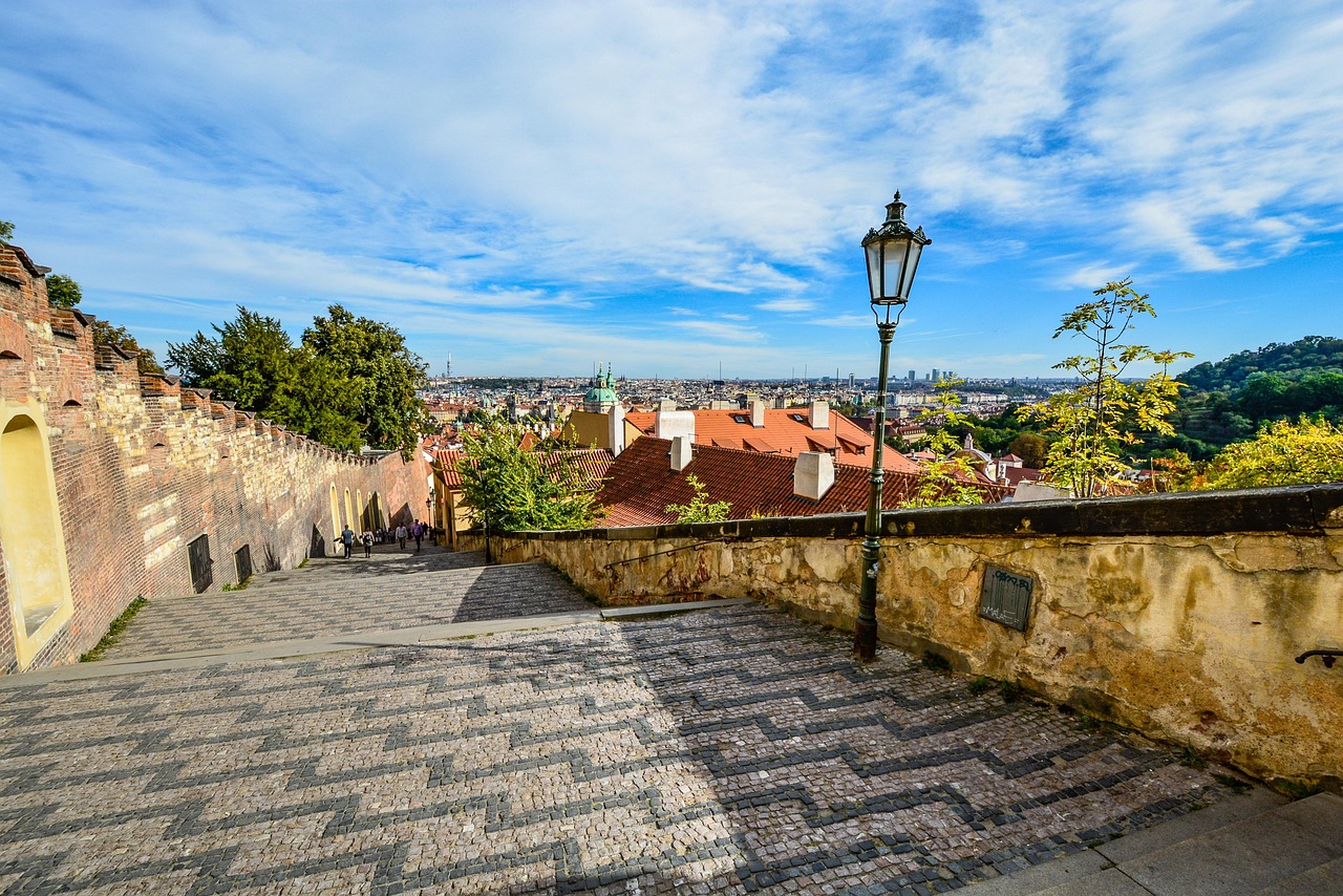 A cobbled stairway descending from the Castle walls toward the rooftops of Lesser Town