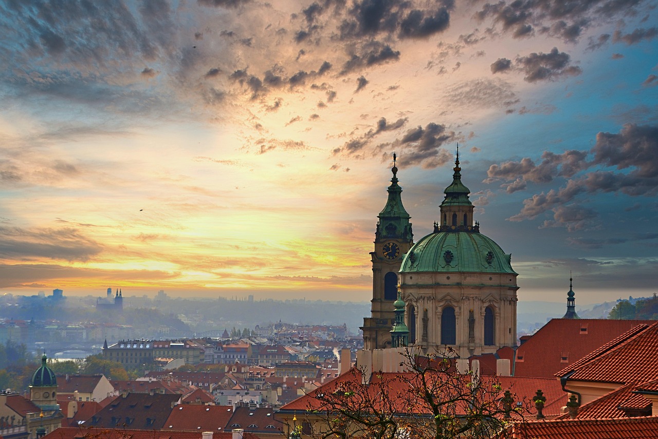 St. Nicholas Church's baroque dome above the red rooftops of Lesser Town at sunset